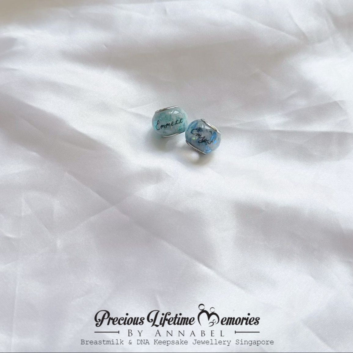 Blue gemstone earrings on a white fabric background with 'Precious Lifetime Memories by Annabel' branding.
