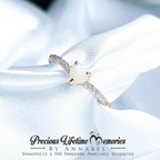 Delicate breastmilk ring with a central gemstone on a white fabric background, featuring 