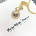Gold keychain with heart-shaped charm on a branded card