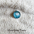 Blue pendant with heart design on a textured white surface, featuring 'Precious Lifetime Memories' branding.