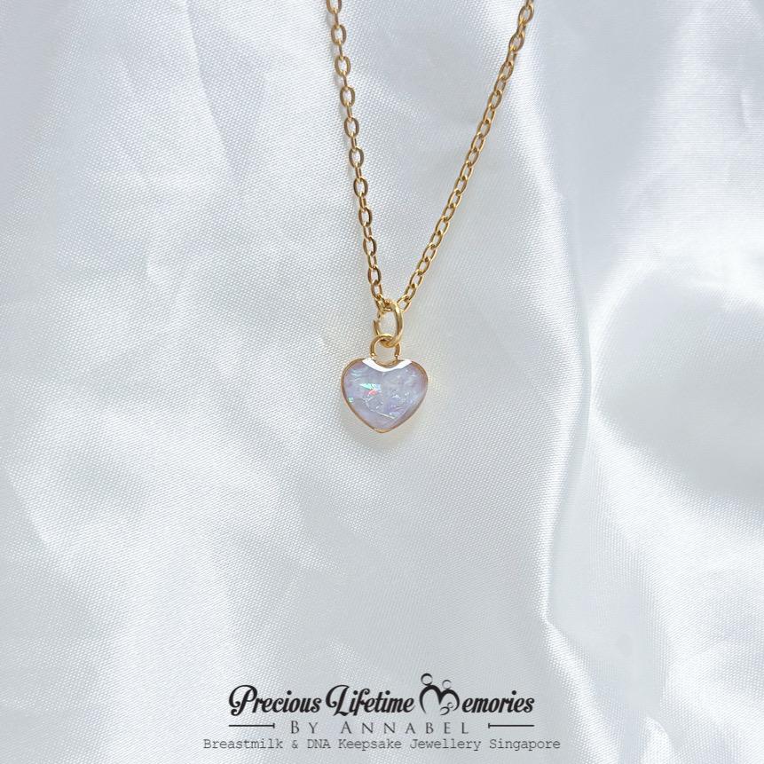 Gold necklace with a heart-shaped pendant on a white fabric background, 母乳项链