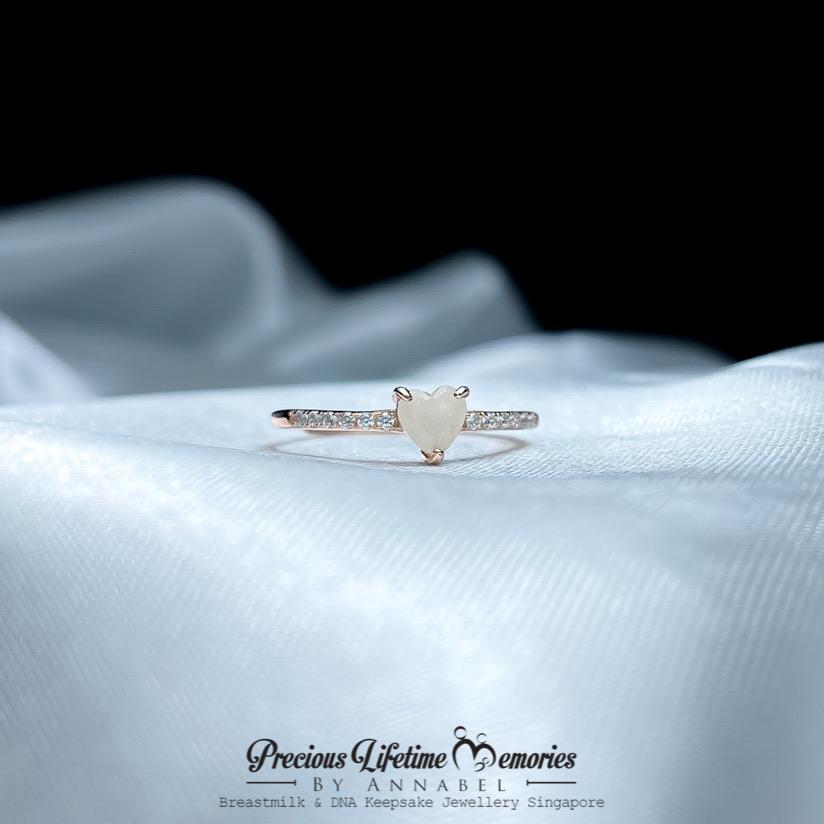 Rose gold ring with a heart-shaped gemstone on a white fabric background, branded 'Precious Lifetime Memories by Annabel'.