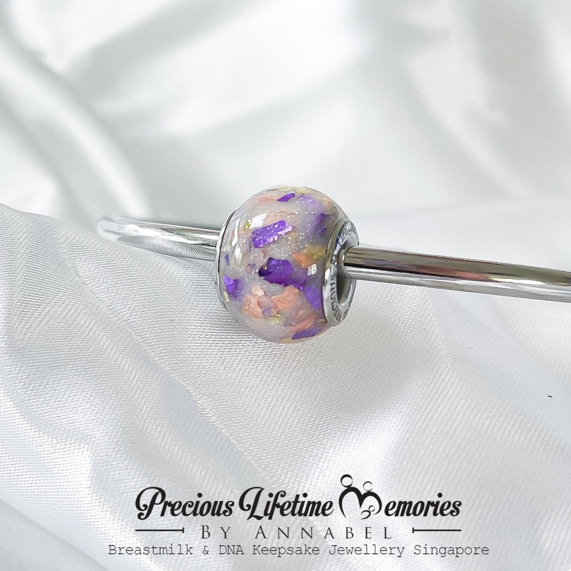 Silver bracelet with a floral bead on a white satin background, featuring 'Precious Lifetime Memories by Annabel' branding.