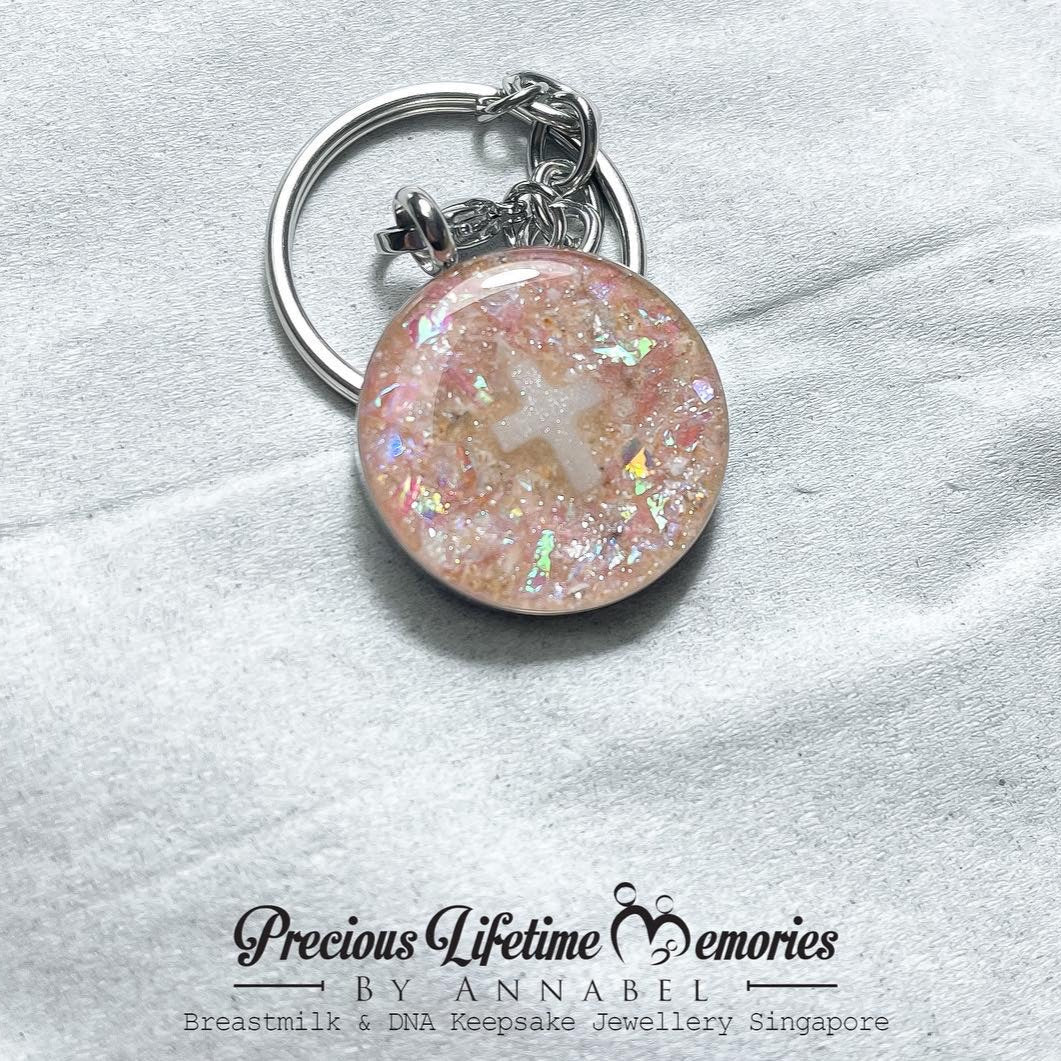 Keychain with pink glittery surface on a white fabric background, featuring 'Precious Lifetime Memories by Annabel' branding.