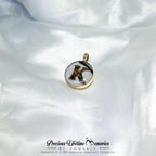 Gold pendant with a black and white design on a white satin background, featuring 'Precious Lifetime Memories by Annabel'.