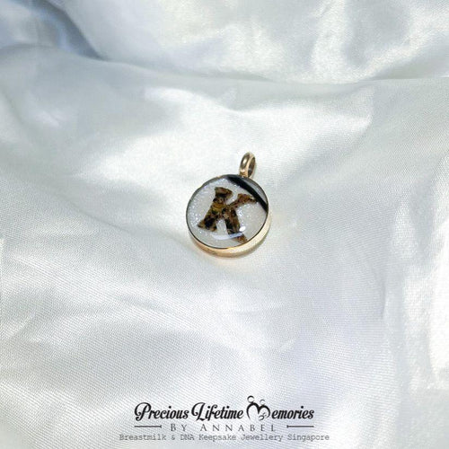 Gold pendant with a black and white design on a white satin background, featuring 'Precious Lifetime Memories by Annabel'.