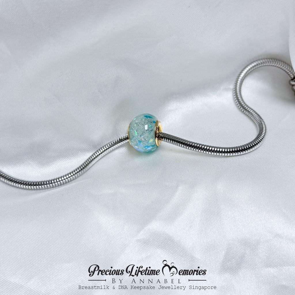 Jewelry charm with a blue gemstone on a white background, featuring 'Precious Lifetime Memories by Annabel'.