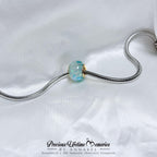 Jewelry charm with a blue gemstone on a white background, featuring 'Precious Lifetime Memories by Annabel'.