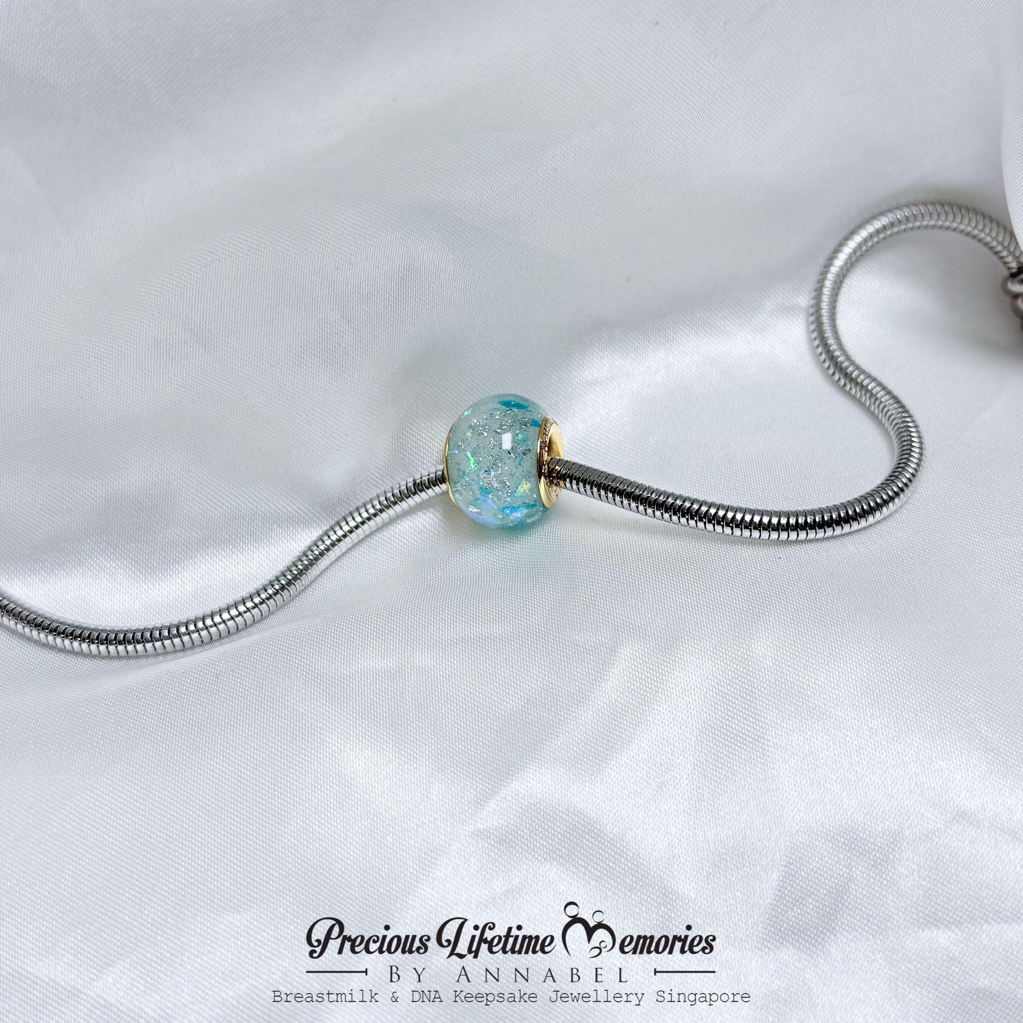 Jewelry charm with a blue gemstone on a white background, featuring 'Precious Lifetime Memories by Annabel'.