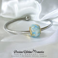 Silver bracelet with a blue and gold bead on a white satin background, featuring 'Precious Lifetime Memories by Annabel'.