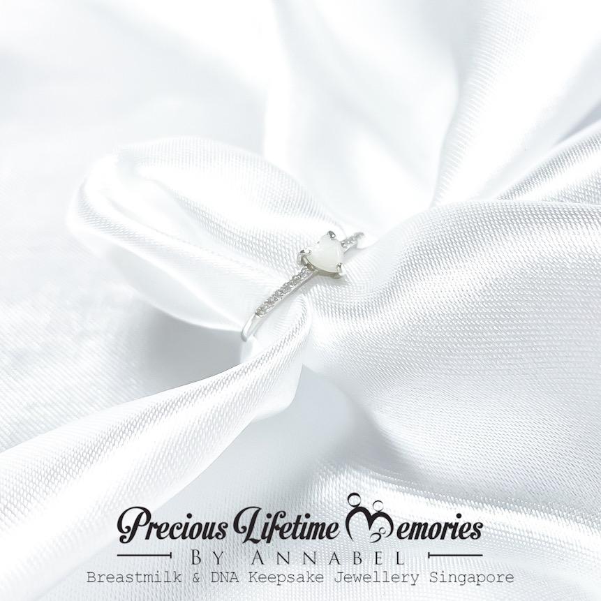Silver earring on white fabric with 'Precious Lifetime Memories keepsake by Annabel' branding.