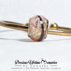 Gold bangle with a decorative clasp on a white background, featuring 'Precious Lifetime Memories by Annabel'.