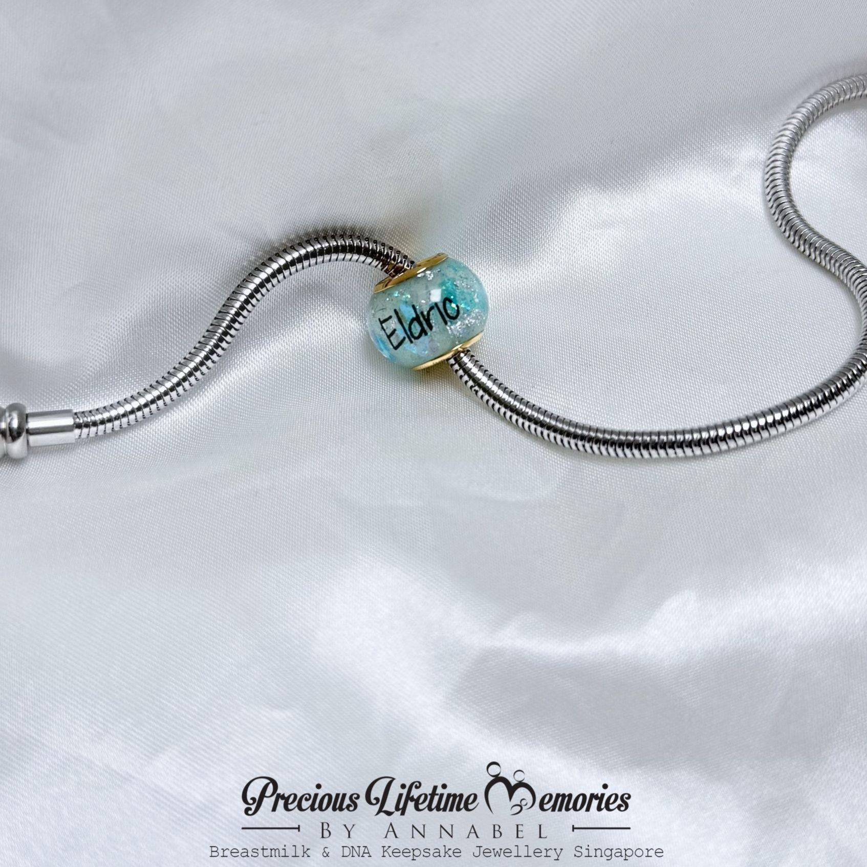 Silver bracelet with a turquoise charm on a white satin background, featuring 'Precious Lifetime Memories by Annabel'.