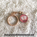 Rose gold keychain with a pink charm on a white fluffy surface