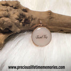 Jewelry with a circular pendant on a textured surface, featuring 'Tasneem Tayyib'.