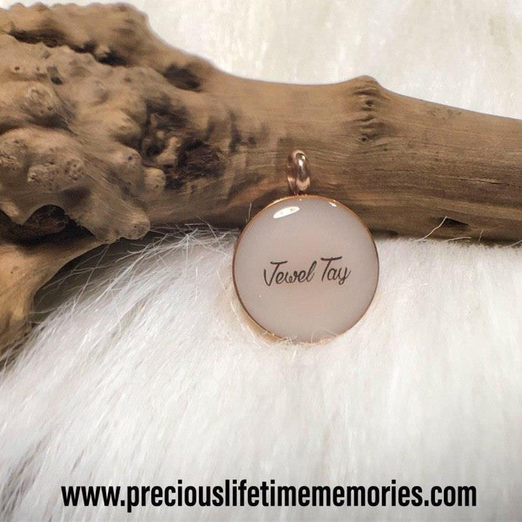 Jewelry with a circular pendant on a textured surface, featuring 'Tasneem Tayyib'.