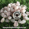 Necklace with a heart pendant and engraved name on a pile of rose quartz stones.