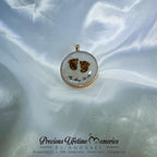 Gold pendant with embedded material on a white fabric background, branded 'Precious Lifetime Memories by Annabel'.