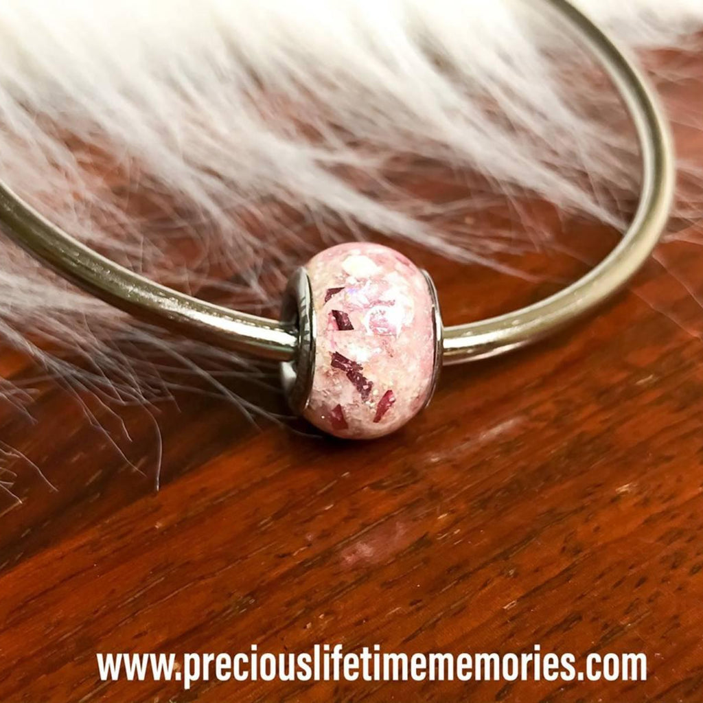 Bracelet with a pink pandora charm bead on a wooden surface with fur