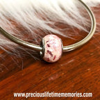 Bracelet with a pink pandora charm bead on a wooden surface with fur