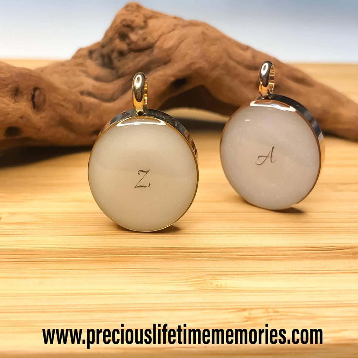 Two round earrings with initials on a wooden surface, featuring a website address.