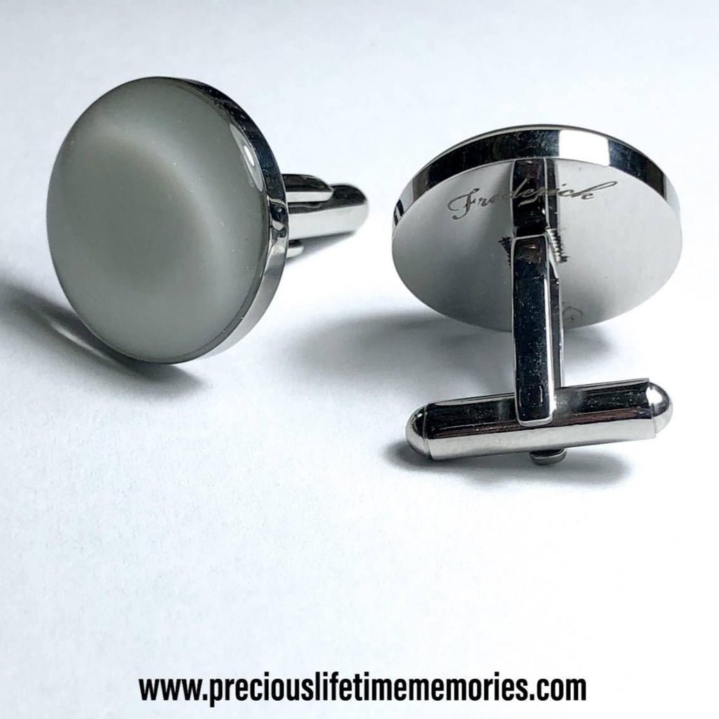 Silver cufflinks on a light gray background with a website address.