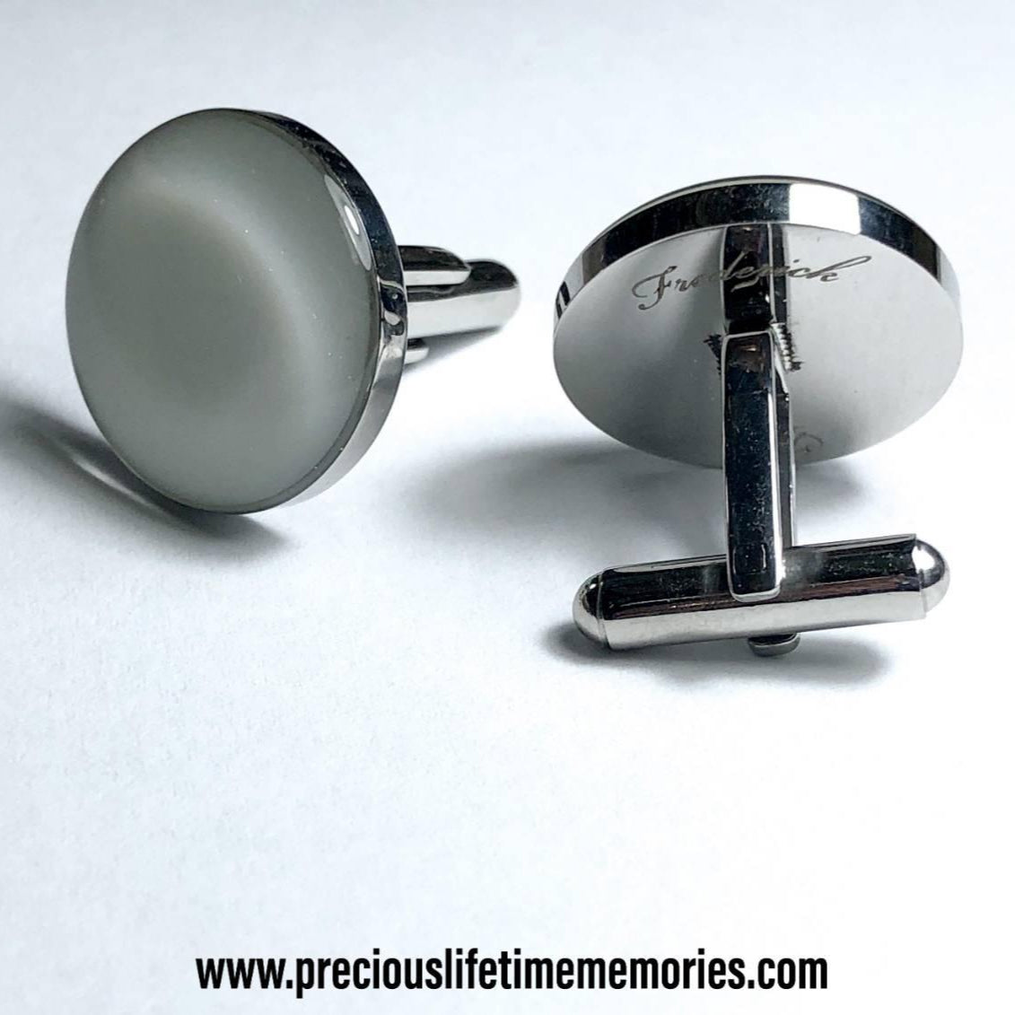 Silver cufflinks on a light gray background with a website address.
