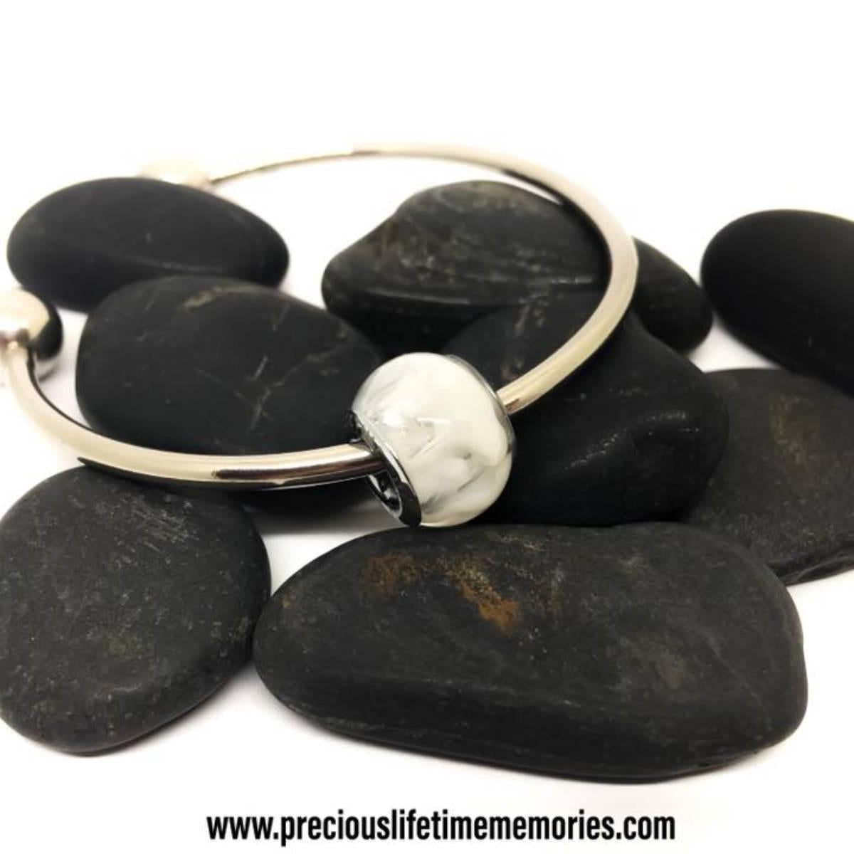 Silver ring with a silver stone on black stones, brand 'preciouslifetimememories.com' visible