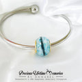 Silver bracelet with a blue and gold bead on a white background, featuring 'Precious Lifetime Memories by Annabel'.