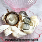Jewelry set with heart-shaped locket and charms on seashells with a pink stand.