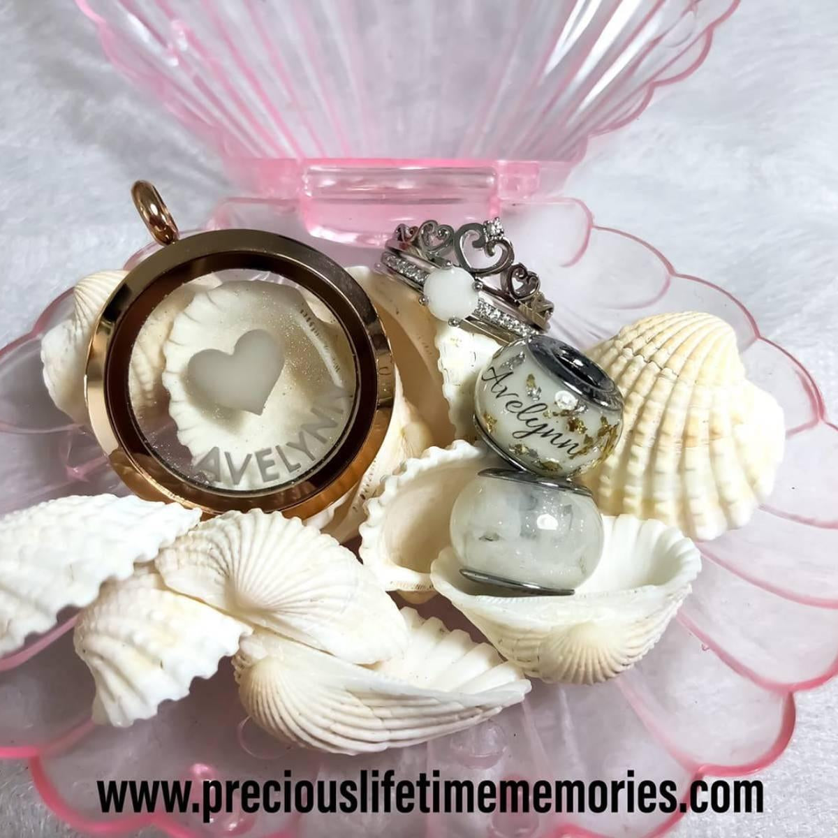 Jewelry set with heart-shaped locket and charms on seashells with a pink stand.