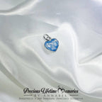 Heart-shaped blue pendant on white satin fabric with 'Precious Lifetime Memories by Annabel' branding.