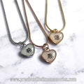 Three heart-shaped pendants on necklaces with Chinese characters against a marble background.