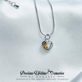 Silver necklace with a heart-shaped pendant on a white satin background, featuring 'Precious Lifetime Memories' branding.