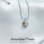 Silver necklace with a heart-shaped pendant on a white satin background, featuring 'Precious Lifetime Memories' branding.