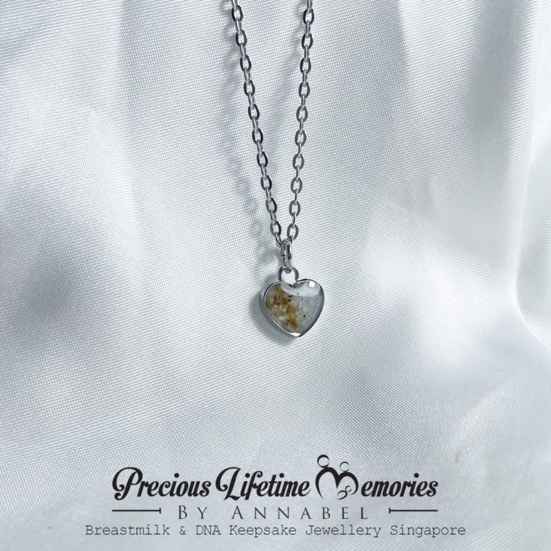 Heart-shaped necklace with a clear pendant on a white fabric background, featuring 'Precious Lifetime Memories by Annabel'.