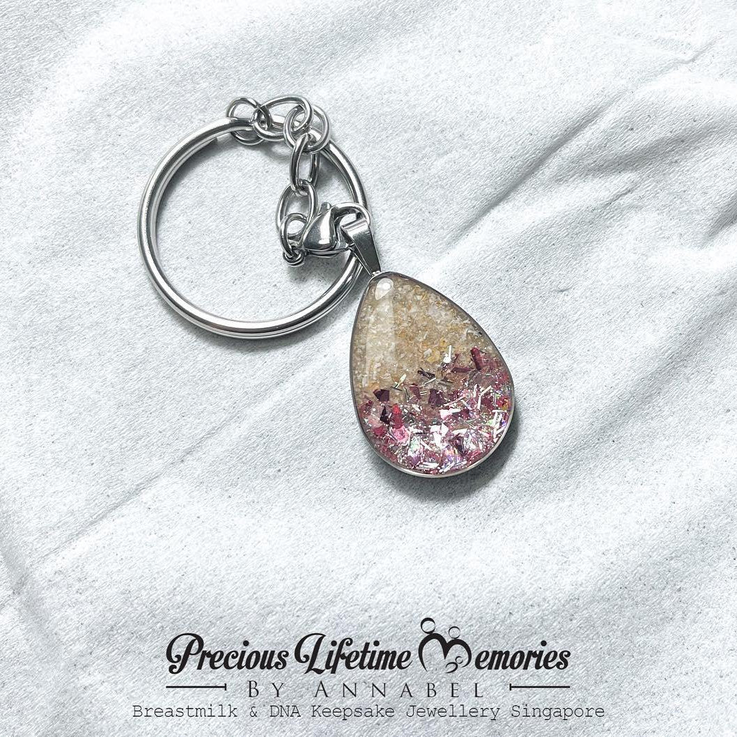 Keychain with teardrop-shaped pink and gold embellishment on a white fabric background