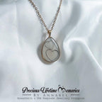 Teardrop-shaped pendant with heart design on a white fabric background, featuring 'Previous Lifetime Memories by Annabel'.