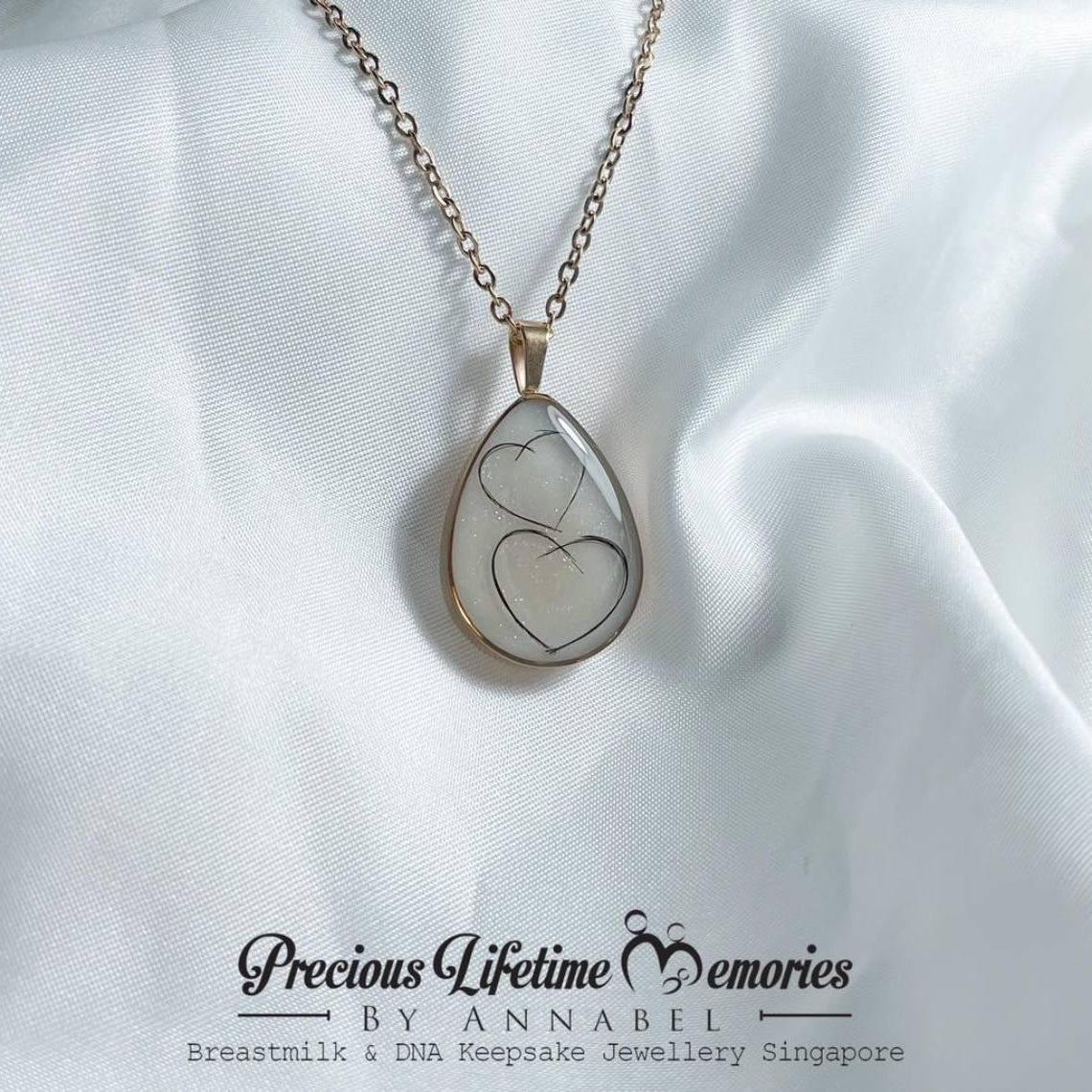 Teardrop-shaped pendant with heart design on a white fabric background, featuring 'Previous Lifetime Memories by Annabel'.