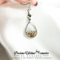 Teardrop necklace with a small chain held by a hand on a white background, 母乳脐带肚脐
