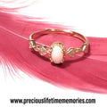 Rose gold ring with a pink gemstone on pink feathers, brand name 'preciouslifetimememories' visible.