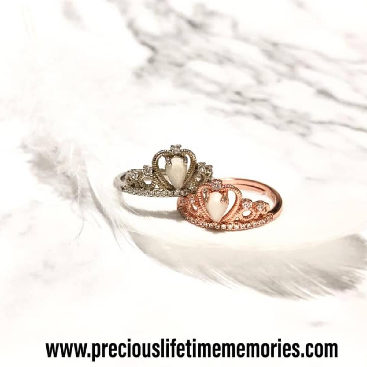 Two heart-shaped rings with crowns on a white feather background, featuring the brand 'preciouslifetimememories.com'.