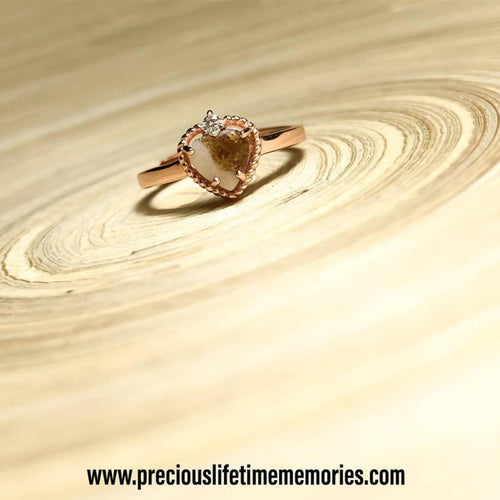 Rose gold ring with a heart-shaped gemstone on a wooden surface, featuring the brand 'preciouslifetimememories.com'.