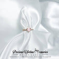 heart ring breastmilk Jewelry with a pink gemstone on white satin fabric, featuring 'Precious Lifetime Memories by Annabel'.