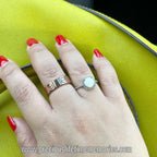 Hand wearing two rings with a yellow background