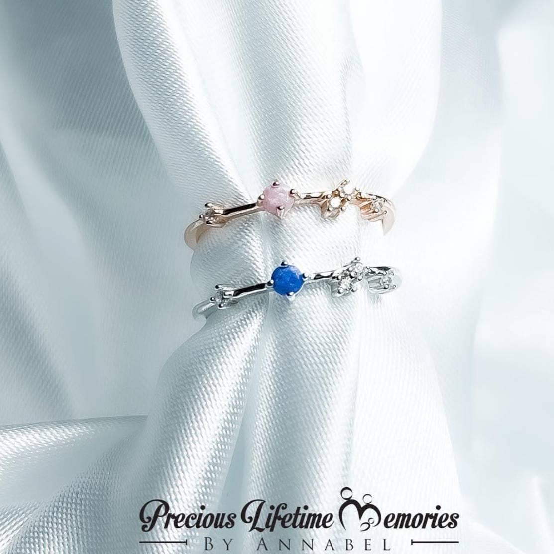 Two rings with gemstones on a white fabric background, featuring the brand 'Precious Lifetime Memories by Annabel'.