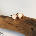 Heart-shaped breast milk earrings on a piece of wood with a light background