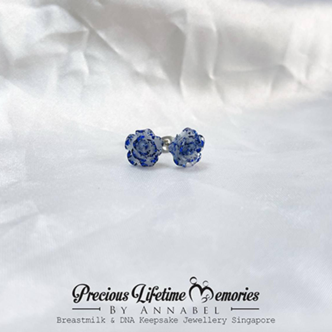 Blue bow-shaped earrings on a white fabric background with 'Precious Lifetime Memories by Annabel' branding.