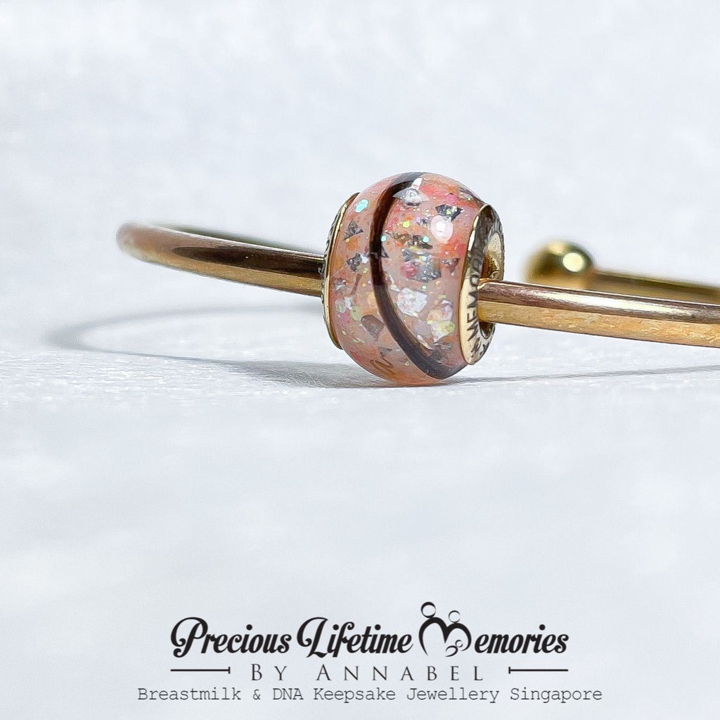 Gold bracelet with a pink charm on a white background, featuring 'Precious Lifetime Memories by Annabel' branding.