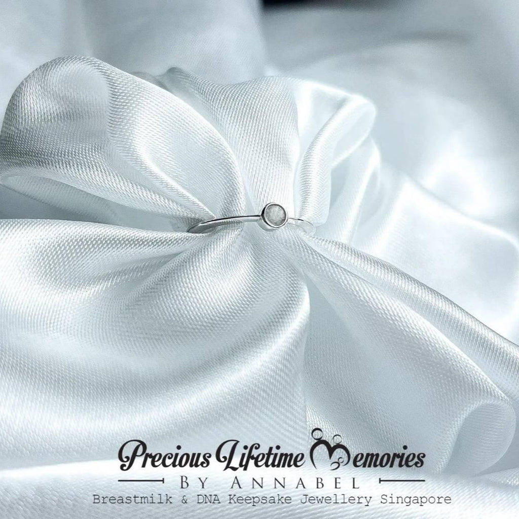 Close-up of white satin fabric with a small jewelry piece on a white background, featuring 'Precious Lifetime Memories by Annabel' branding.